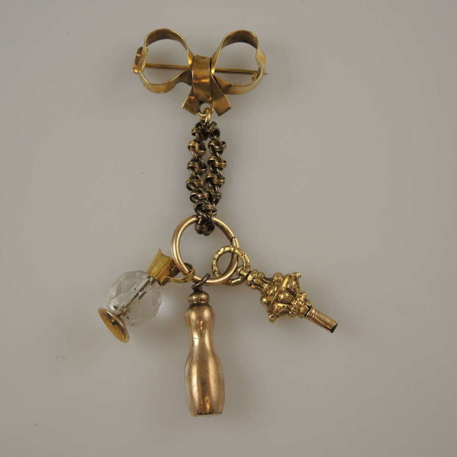 Victorian gold bow pin with a selection of charms inc pocket watch key